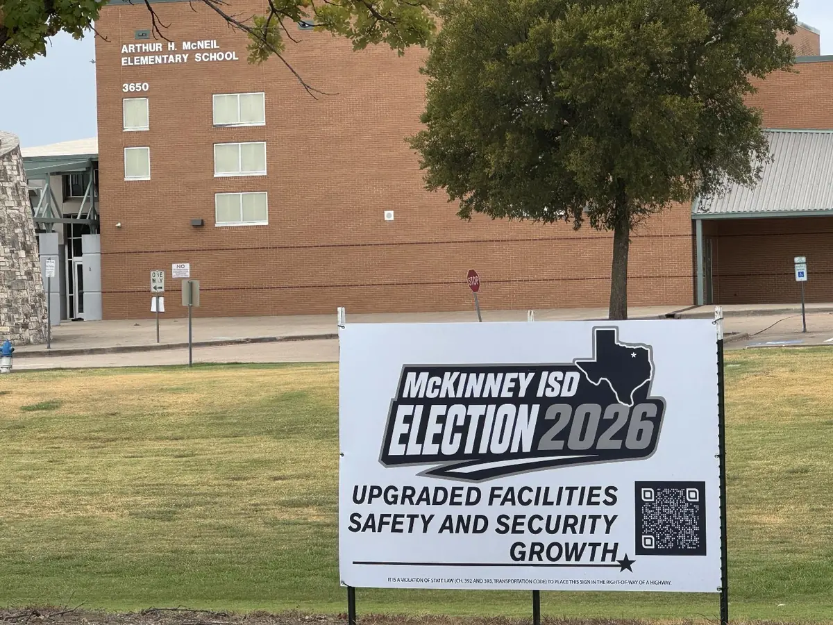 A white McKinney ISD Election 2026 sign on the lawn in front of the brick Arthur H. McNeil Elementary School building.